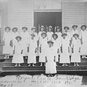 African-American women in matching dresses with hats on steps of building