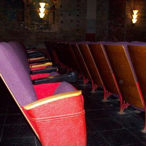 Interior of theater with rows of seats with armrests and light on brick wall