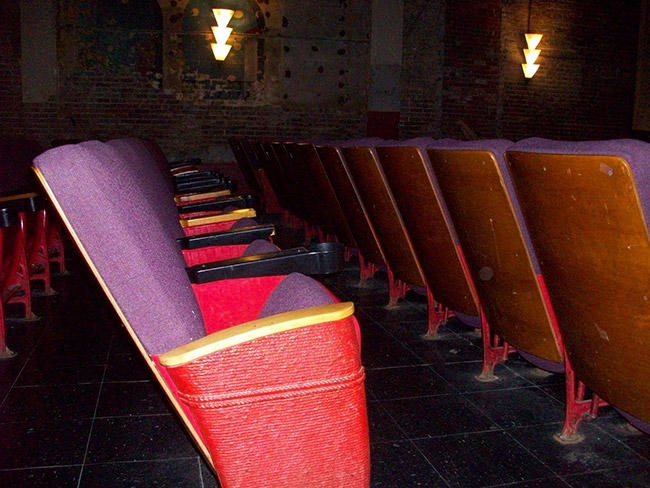 Interior of theater with rows of seats with armrests and light on brick wall
