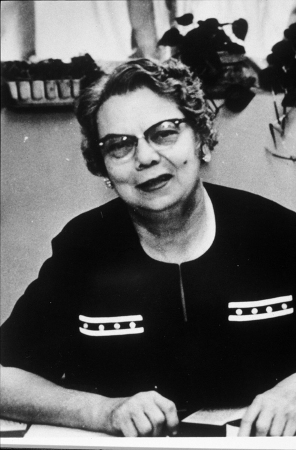 Older white woman with glasses sitting at desk