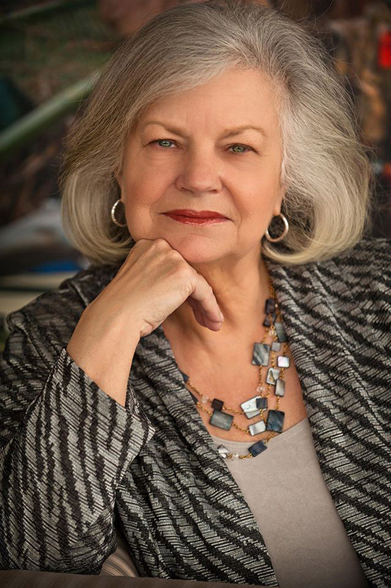 Older white woman with long gray hair in striped shirt and earrings