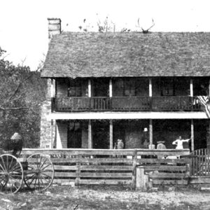 Two-story house with wooden fence and horse drawn wagon