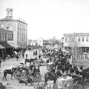 Street filled with people and horses with carts and buggies