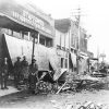 Group of white men and women standing outside "Stafford's Dry Goods, Clothing, and Shoes" store, the front overhang of which has collapsed