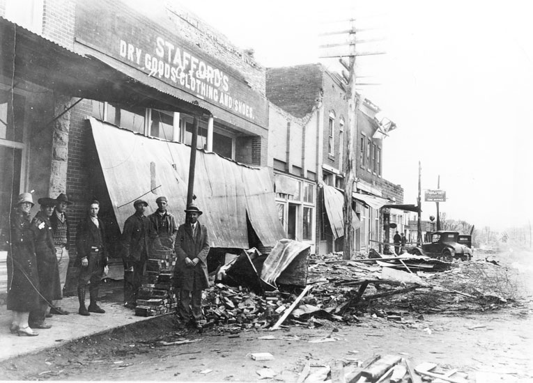 Group of white men and women standing outside "Stafford's Dry Goods, Clothing, and Shoes" store, the front overhang of which has collapsed