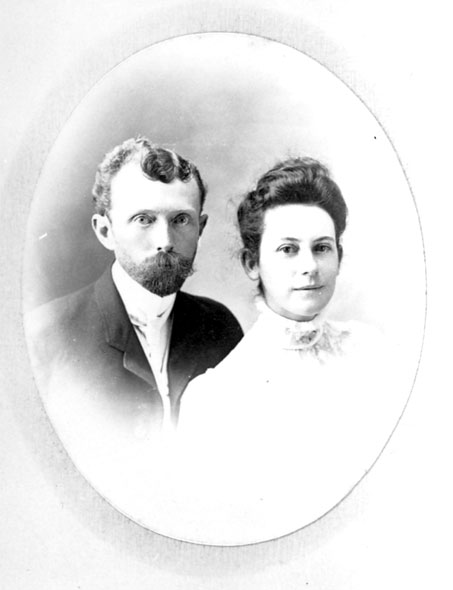 White man with a mustache in suit and woman in white dress