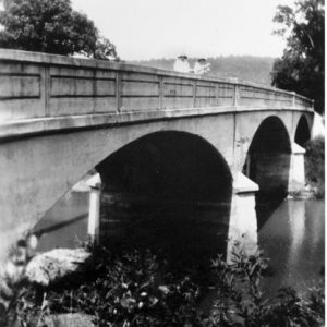 Concrete arched bridge over a river with two women standing on it