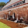 Cotton farmers painted on exterior mural of brick building with banner text "Southern Tenant Farmers Museum"