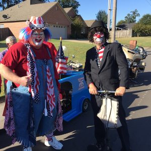White clowns and men in red hats with vehicles in residential neighborhood