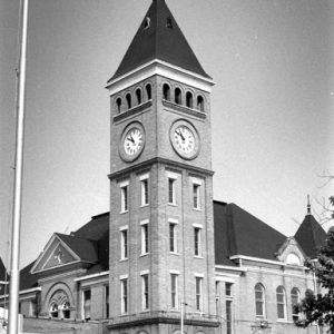 Multistory brick courthouse with tall clock tower and arched entrances