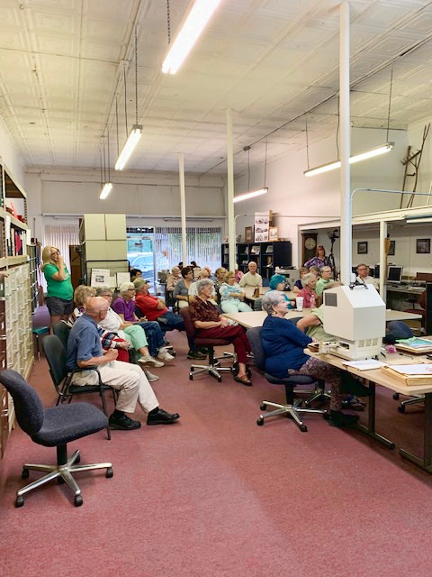 Crowd of older white men and women sitting in archives research room