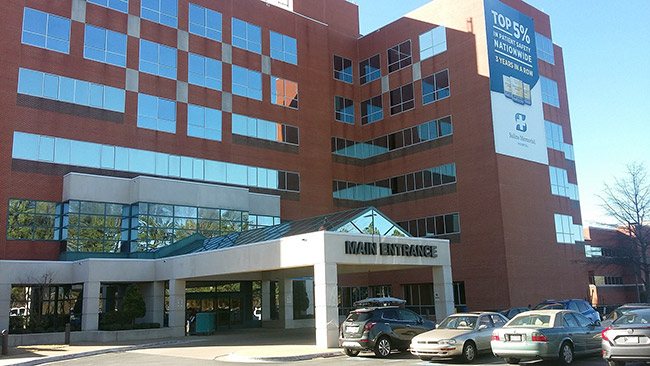 Multiple-story brick hospital building with covered entrance and parking lot