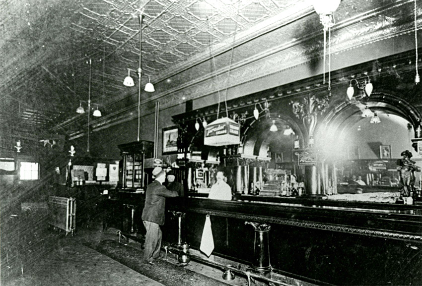 Bar tender and patron standing at saloon bar