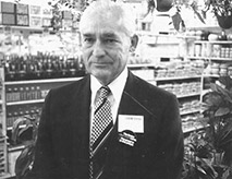 Old white man in suit and tie standing in store