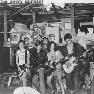 Group of young white men with electric guitars bass and drumsticks in garage studio