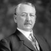 White man with glasses and mustache in suit and tie