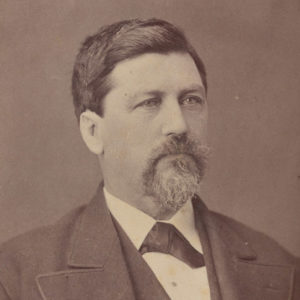 White man with mustache and beard in suit and bow tie