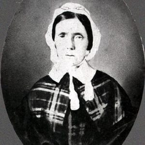 Older white woman wearing a bonnet and dress with collar