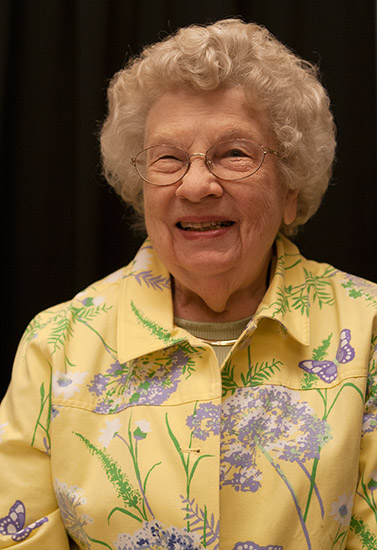 smiling older white woman with glasses in yellow floral shirt