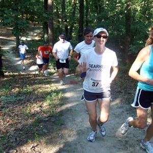 White men and women running on a forest trail