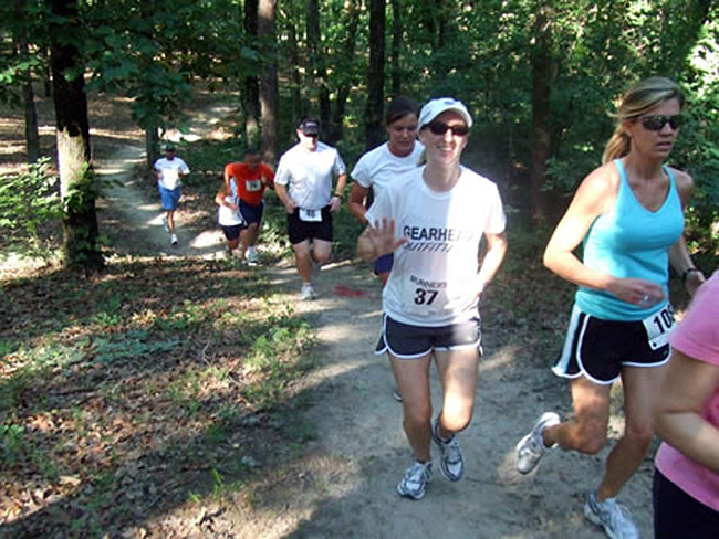 White men and women running on a forest trail