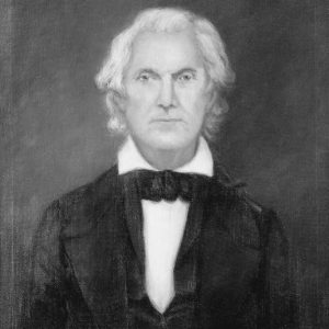 White man with long white hair in suit and bow tie