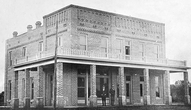 Two-story brick hotel building with two white men in uniform