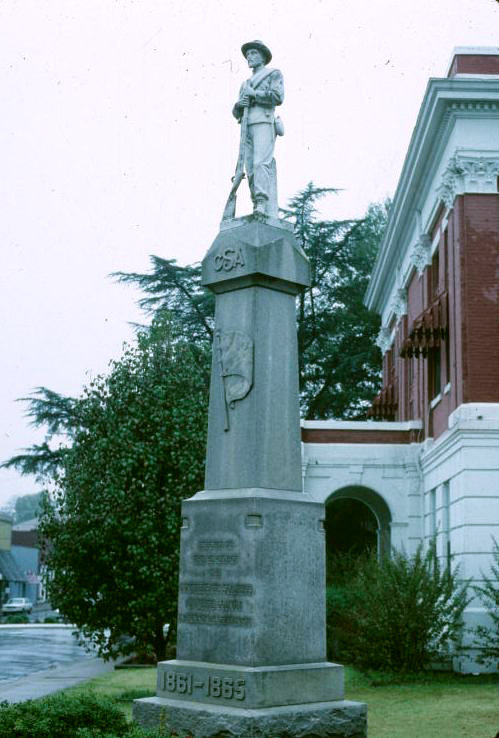 statue of soldier with gun on top of "C.S.A." monument next to brick building on street corner