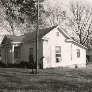 Side view of single-story house with telephone pole outbuilding and power lines