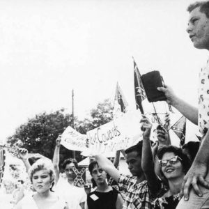 Group of young white men and women waving Confederate battle flags carrying a protest banner