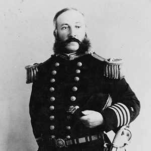 White man with muttonchop sideburns standing in military uniform with sword