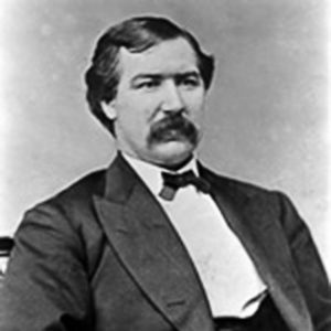 White man with mustache sitting in suit and bow tie