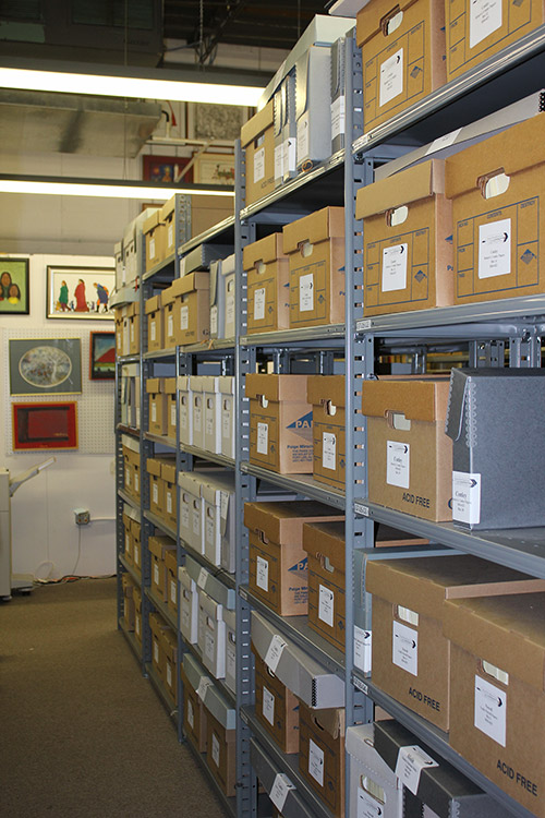 Interior of archives with framed artwork on the walls and materials in boxed on multiple shelves