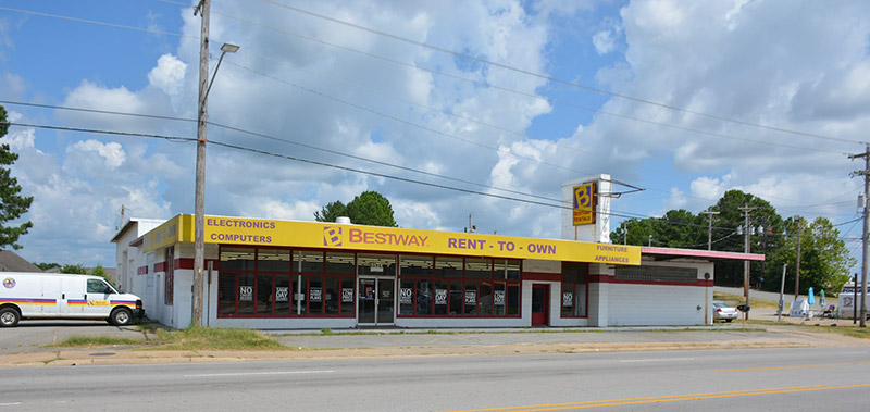 Single-story "Bestway" store with sign and parking lot on street