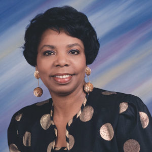 African-American woman smiling in top with circles on it and earrings