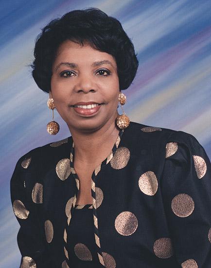 African-American woman smiling in top with circles on it and earrings