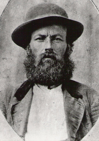 White man with long beard in hat and suit