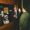 White men and woman looking at press exhibit behind glass