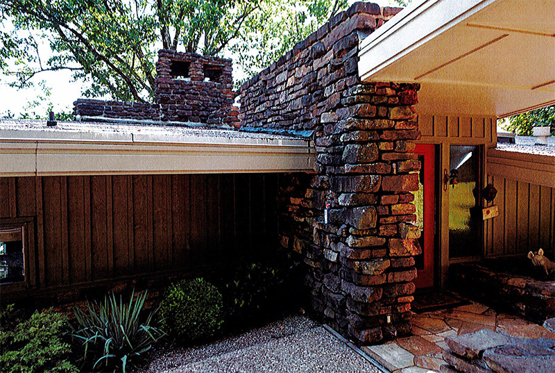 Covered entrance with stone wall and chimney