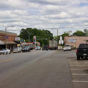Town street with traffic brick storefronts and service station on the left and buildings on the right