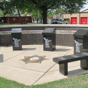 Engraved monuments with bench and brick wall on concrete platform with star shield in its center