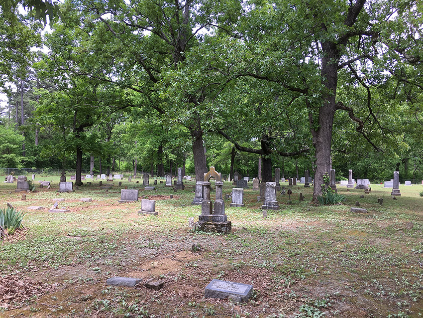 Gravestones in cemetery with trees in the background