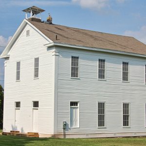 Multistory building with belfry on its roof and white siding