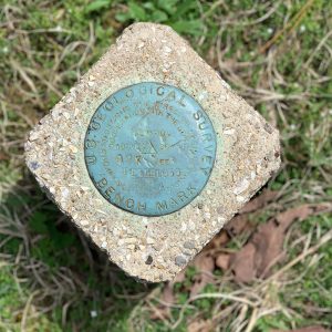 Stone square with engraved round blue marker on grass