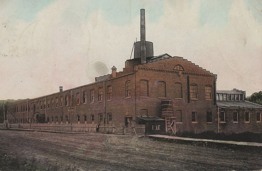 Long brick building with smokestack, water tower
