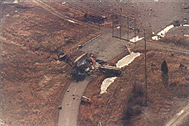 Debris on two-lane road behind gate as seen from above