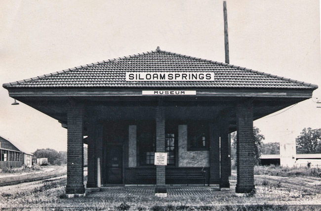 Front view of single-story brick train depot building labeled "Siloam Springs Museum"