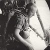 White man in military uniform looking out of an airplane in flight