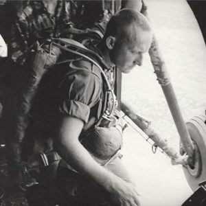 White man in military uniform looking out of an airplane in flight