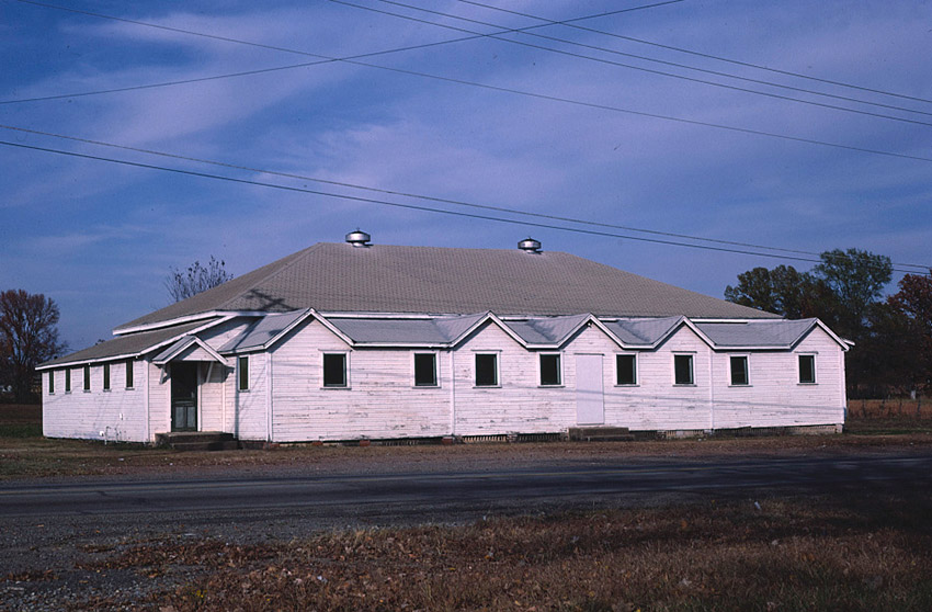 Single-story building with wood siding and hip roof on street